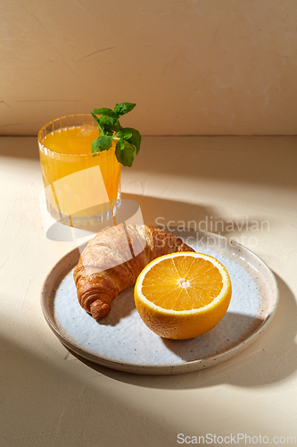 Image of glass of orange juice and croissant on plate