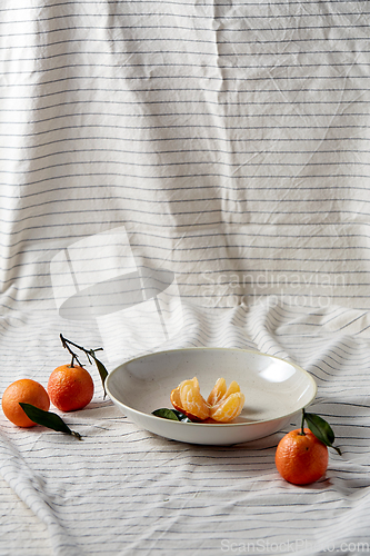 Image of still life with mandarins on plate over drapery