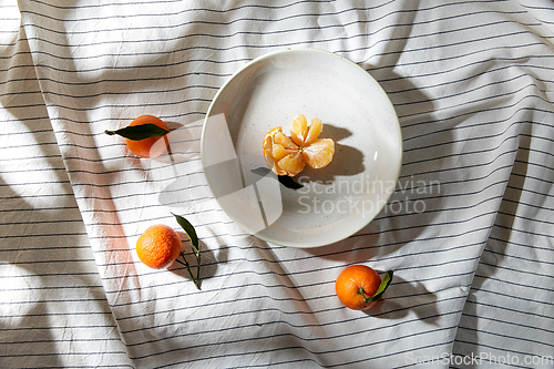 Image of still life with mandarins on plate over drapery