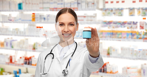 Image of smiling female doctor holding jar of medicine