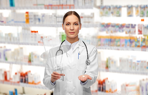 Image of doctor with pills and glass of water at pharmacy