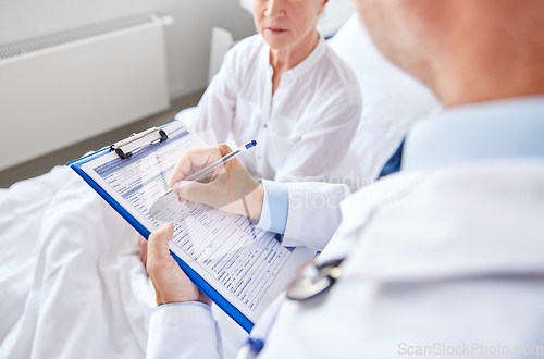 Image of senior woman and doctor with clipboard at hospital