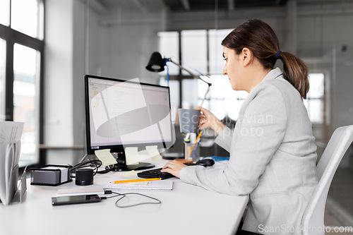 Image of businesswoman with computer and coffee at office