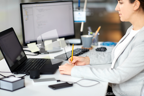 Image of businesswoman with notebook and laptop at office