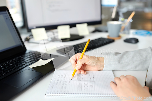 Image of businesswoman with notebook and laptop at office