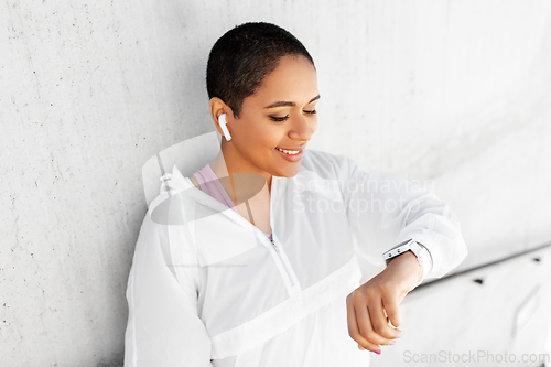 Image of african woman with earphones and smart watch