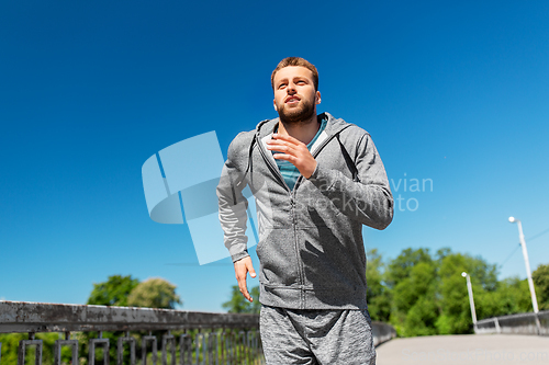 Image of happy young man running across city bridge