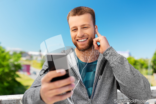 Image of smiling young man with earphones and smartphone