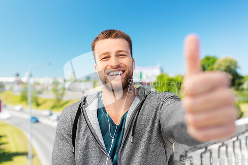 Image of happy smiling man in earphone showing thumbs up