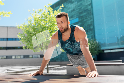 Image of young man doing push ups on city street