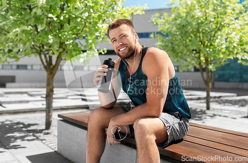 Image of sportsman with earphones and bottle in city