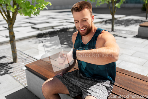 Image of happy man with smart watch sitting on bench