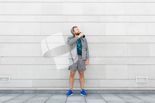 Image of sportsman with bottle drinking water in city