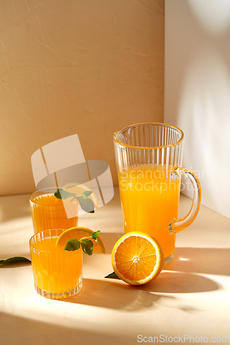 Image of glasses with orange juice and peppermint on table