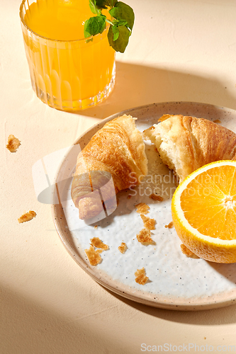 Image of glass of orange juice and croissant on plate