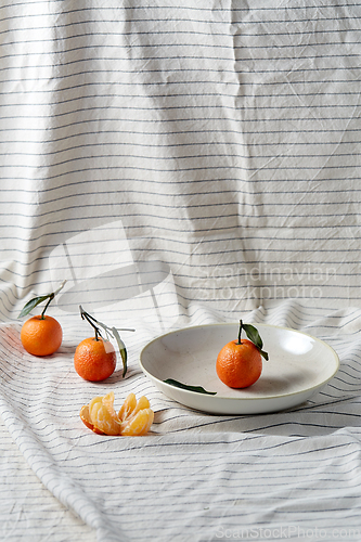 Image of still life with mandarins on plate over drapery