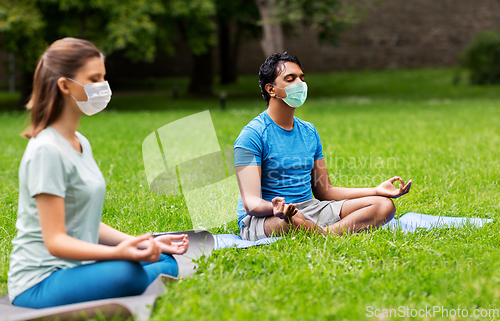 Image of group of people doing yoga at summer park