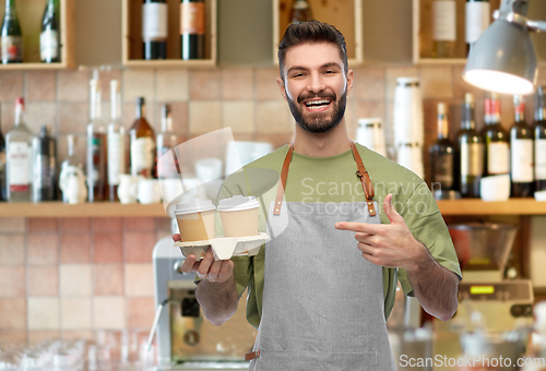 Image of happy smiling barman in apron with takeaway coffee