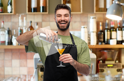 Image of happy barman with shaker and glass preparing drink