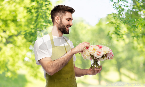 Image of smiling male gardener with bunch of peony flowers