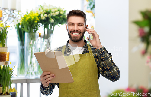 Image of male gardener with clipboard calling on smartphone