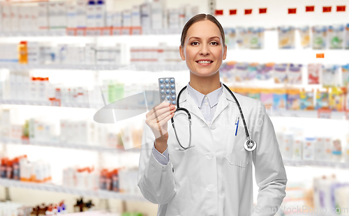 Image of smiling female doctor holding medicine pills