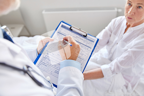 Image of senior woman and doctor with clipboard at hospital