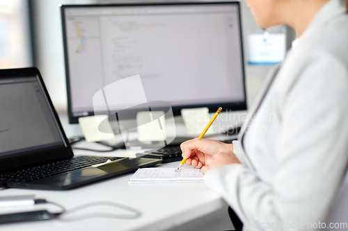 Image of businesswoman with notebook and laptop at office