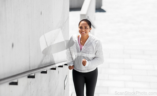 Image of african american woman running upstairs outdoors