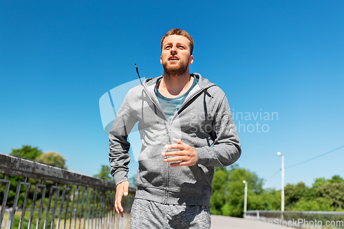 Image of happy young man running across city bridge