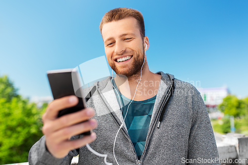 Image of smiling young man with earphones and smartphone