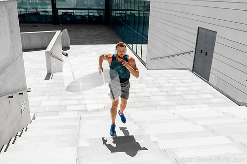 Image of young man in headphones running upstairs outdoors