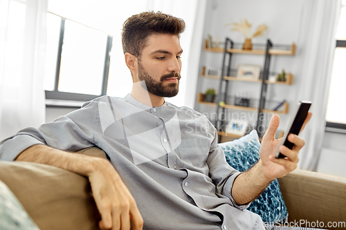 Image of young man with smartphone at home