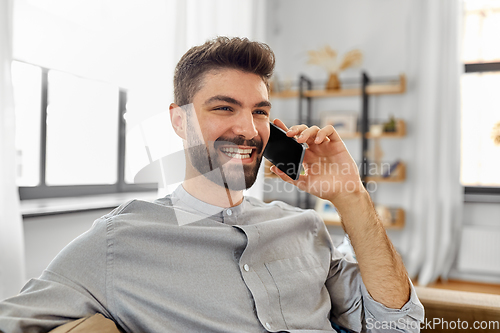 Image of happy man calling on smartphone at home