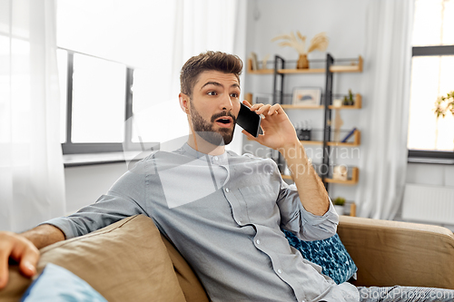 Image of man calling on smartphone at home