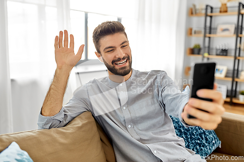 Image of man with smartphone having video call at home