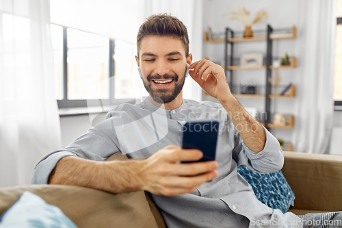 Image of man in earphones listening to music on smartphone