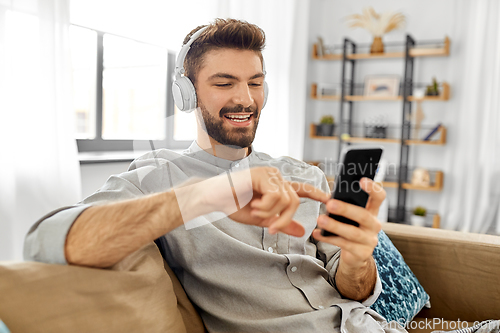 Image of man in headphones listening to music on smartphone