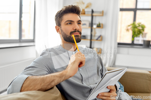 Image of man writing to notebook and thinking at home