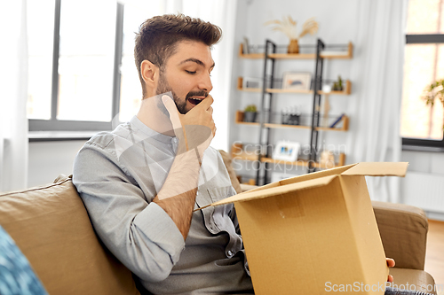 Image of happy smiling man with open parcel box at home