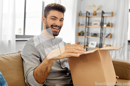 Image of happy smiling man opening parcel box at home