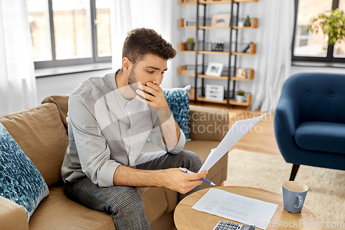 Image of stressed man with bills at home