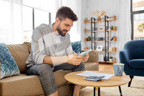 Image of man with money and calculator filling papers