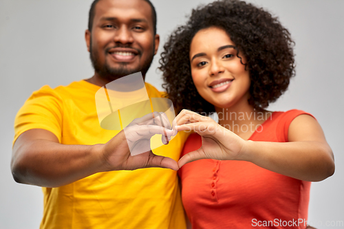 Image of happy african american couple making hand heart