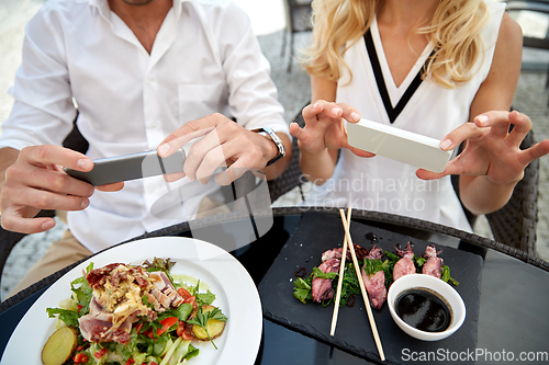 Image of couple with smatphones photographing food