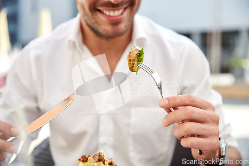 Image of close up of happy man eating food at restaurant