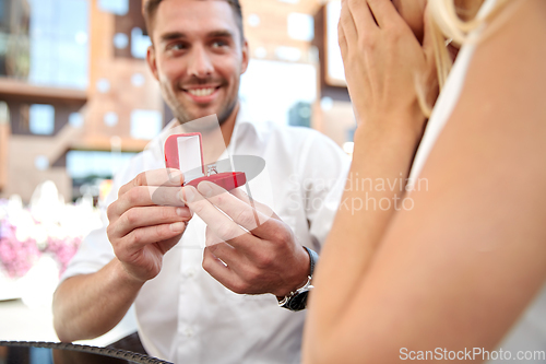 Image of close up of man giving engagement ring to woman