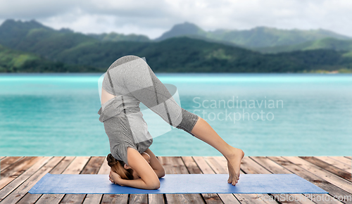 Image of woman making yoga in headstand pose over ocean