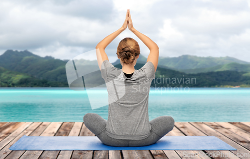 Image of woman doing yoga in lotus pose over ocean