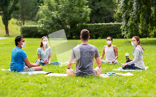 Image of group of people sitting on yoga mats at park